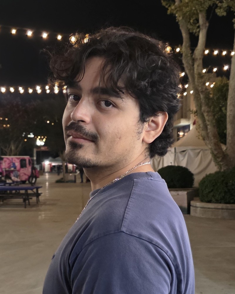 Jairo Mendoza, a portrait taken at night under string lights